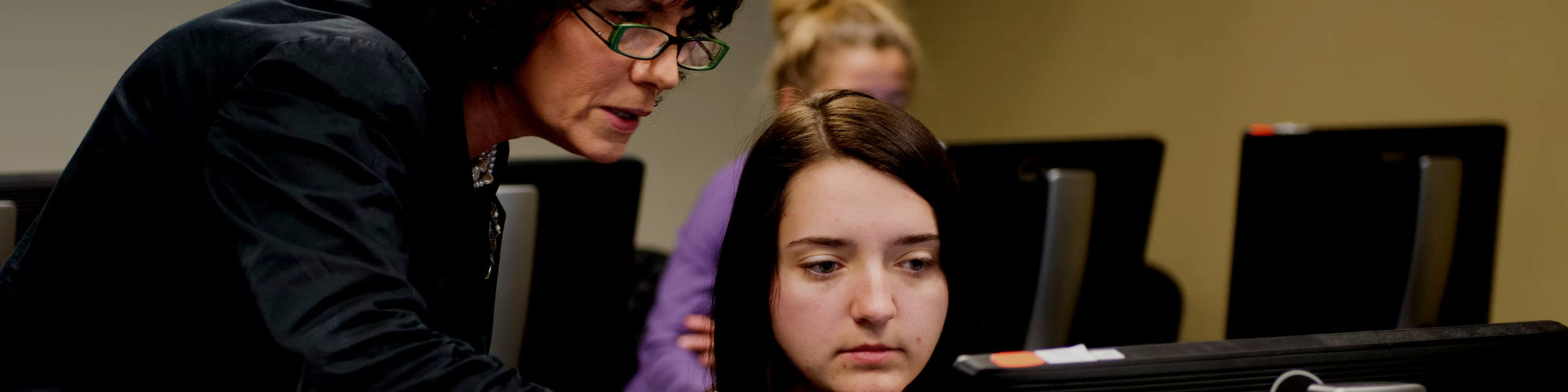 Professor talking to a student looking to a computer screen