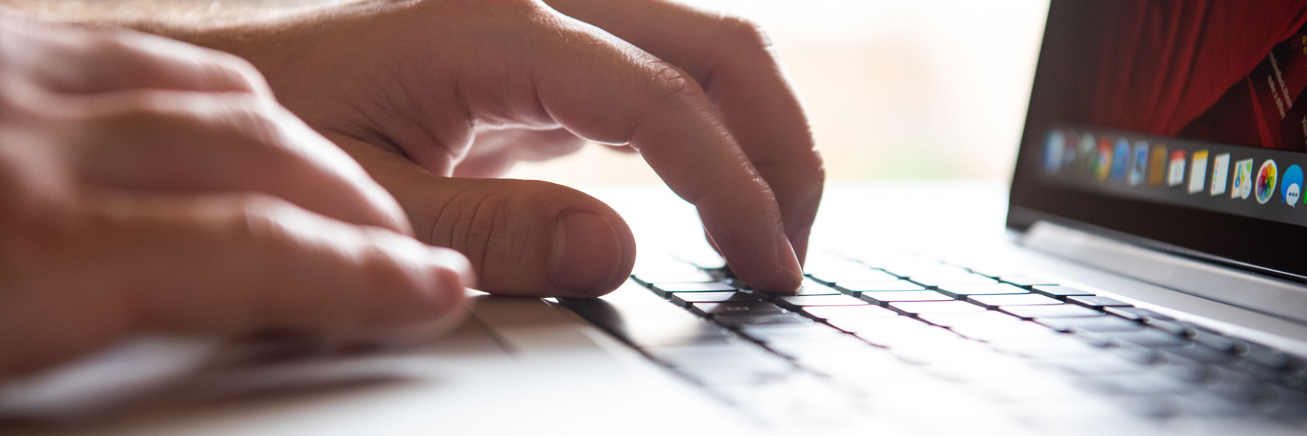 Hands typing on a laptop